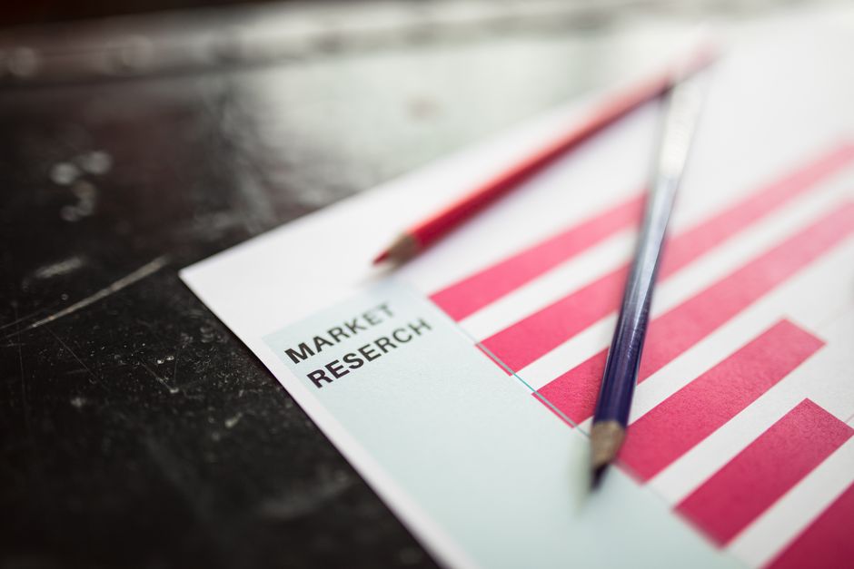Close-up of market research paper with red graph bars and pencils, emphasizing business analysis.